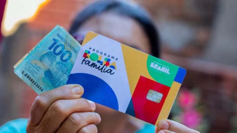 Beneficiários do Bolsa Família retirando segurando o cartão do programa e dinheiro